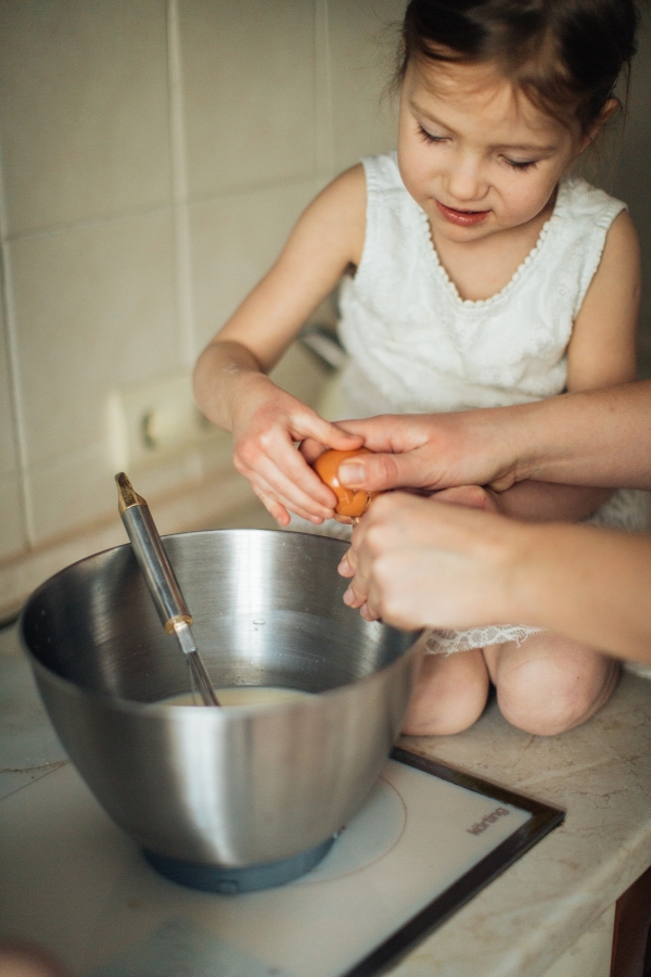 Girl craking an ege into mixing bowl