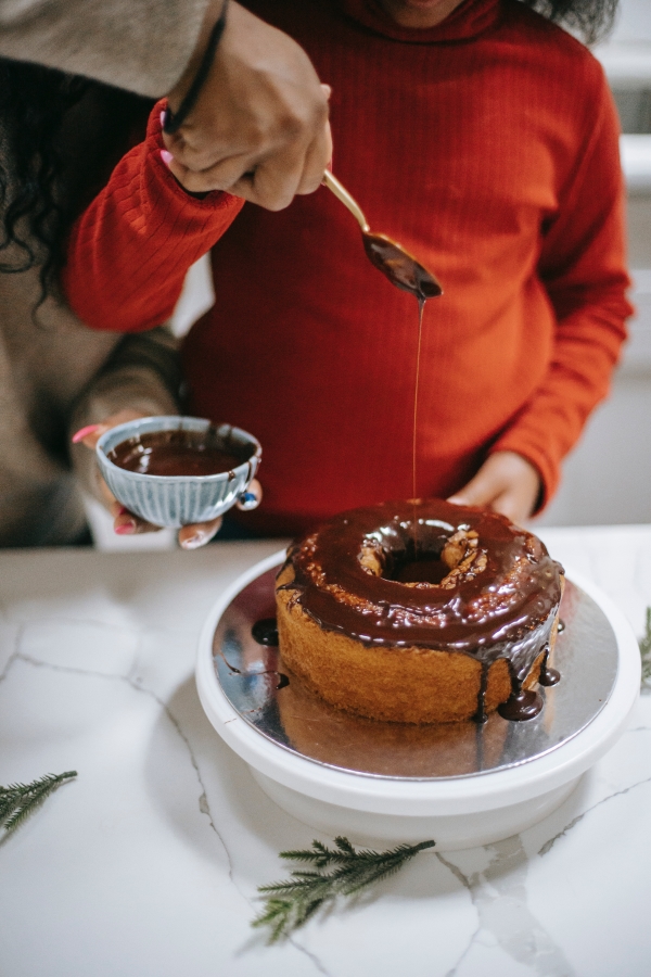 student pouring chocoalte over cake